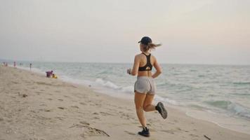 Frau, die Ozeanstrand läuft. junge asiatische Frau, die im Freien trainiert und an der Küste läuft. Konzept des gesunden Laufens und der Bewegung im Freien. aktiver, sportlicher Sportler beim Joggen. Sommer aktiv