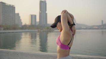 Young sportive woman doing stretching exercises. Girl resting after exercise outdoors. Athletic woman stretching against a tree. fit sportswoman doing warming up exercises video