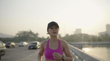 Frau beim morgendlichen Joggen. folgende Zeitlupen-Rückansicht. Fitness-Läufer-Training. Sonniger Himmel mit Wolken bei Sonnenuntergang oder Sonnenaufgang. Jogger am Steg am See. sportliche Motivation. video