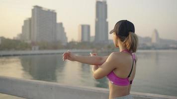 Young sportive woman doing stretching exercises. Girl resting after exercise outdoors. Athletic woman stretching against a tree. fit sportswoman doing warming up exercises video