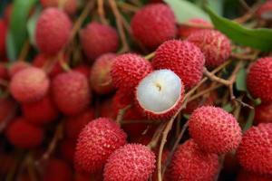 lichi, lichi fresco y pelado que muestra la piel roja y la pulpa blanca con hoja verde. foto