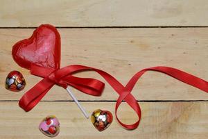 corazón de chocolate envuelto en cinta roja y roja sobre madera. concepto de San Valentín. espacio para texto. foto