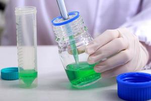 Woman scientist biochemist at the workplace makes the analysis in the modern laboratory. She is holding a dropper and a test tube photo