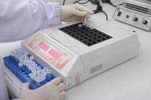 Woman scientist biochemist at the workplace makes the analysis in the modern laboratory. She is holding a dropper and a test tube photo