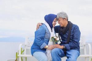 pareja de ancianos asiáticos. una alegre y agradable pareja romántica senior está sentada y sosteniendo una flor blanca mientras se miran. foto