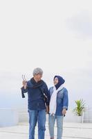 Close-up of romantic senior couple in casual style is walking together while talking and smiling against blue sky. Elderly couple lifestyle concept. photo