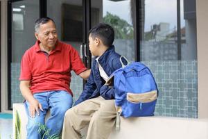 Grandfather talking with his grandson, after school in the house yard. Parenting and family activity concept. photo