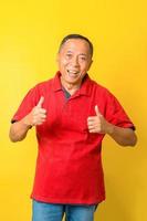 un anciano asiático con una camiseta informal sobre un fondo amarillo aislado haciendo un gesto de aprobación con la mano. expresión de aprobación mirando a la cámara que muestra el éxito. foto