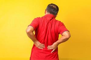 Asian Elderly man experiencing back pain isolated on yellow background photo