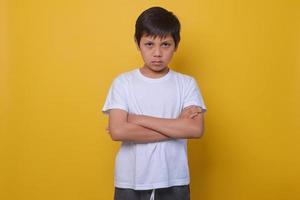 Asian boy in a casual style feeling annoyed and showing sad expression on yellow background. photo