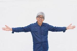 Happy senior man in casual style spreads his arms welcoming and greeting you on white background.  Banner promotion. photo