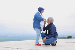 Romantic elderly couple. Husband is on bended  knee and kissing his wife hand. photo