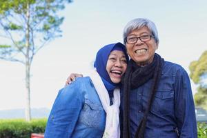 Happy elderly couple laughing at tea plantation. Big smile white teeth. photo