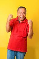 Attractive Asian senior man wearing casual shirt celebrating success with arms raised and beamed teeth. Yes, oh yeah moment. photo