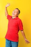 Asian senior man in casual style feel free stretching his hand and smiling isolated on yellow background. photo
