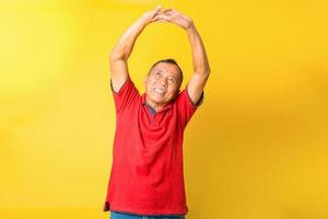 Asian senior man stretching his hand and smiling isolated on yellow background. photo