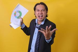 Angry boss screaming and showing a growth graph of bad report isolated on yellow background photo
