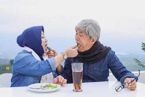 pareja de ancianos asiáticos en un desayuno romántico. esposa y esposo se alimentan mutuamente contra el cielo azul. foto