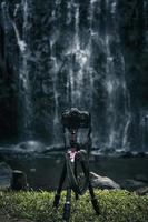 Modern camera is set on tripod for landscape photography in front of waterfall. photo