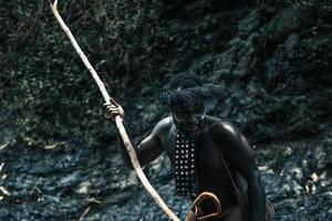 Potrait of Dani tribe man from Wamena Papua Indonesia wearing traditional clothes is spearing prey. photo