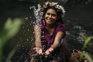 wamena, papúa, indonesia, 01 de junio de 2022 agua salpicada de primer plano contra el fondo borroso de una joven tribu papú usando una corona de plumas en el río. foto