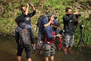Bandung, Indonesia, May, 2022 A group of nature landscape photographers taking picture together at the river. photo
