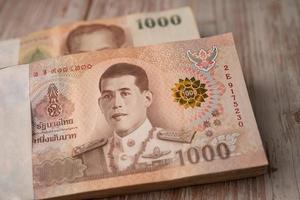 Stack of Thai baht banknotes on wooden background, business saving finance investment concept. photo