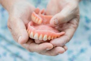 Asian senior or elderly old woman patient holding to use denture in nursing hospital ward, healthy strong medical concept photo