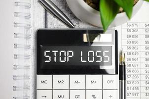 calculadora con texto de stop loss en la pantalla y bolígrafo foto