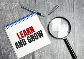 Learn and grow text on notepad and pen on wooden background photo