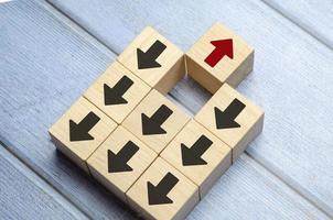 Wooden block with red arrow facing the opposite direction black arrows photo