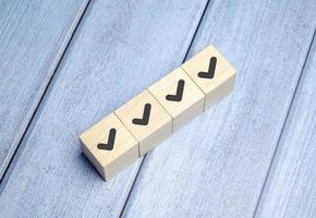 Checklist and check mark concept. Check mark on wooden blocks on light blue background photo