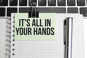 On the table laptop and notepad with text it's all in your hands photo