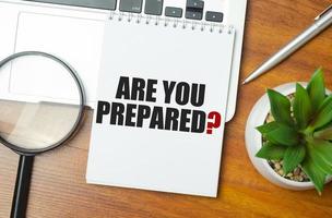 Are You Prepared text on notepad and laptop on wooden background photo