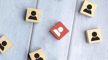 Red wooden cube with person icon stand out from the crowd on blue background. photo