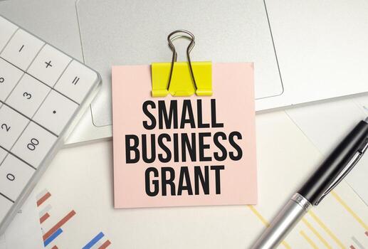 SMALL BUSINESS GRANTS text on folder with chart and calculator photo