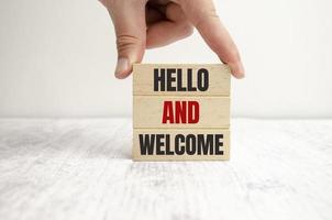 Hello and welcome symbol. Concept words Hello and welcome on wooden blocks. Businessman hand. photo