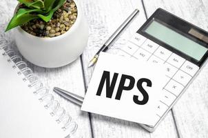 Text NPS on paper card and calculator on wooden background photo