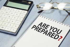 Are You Prepared Question text on notepad and glasses, calculator on wooden background photo