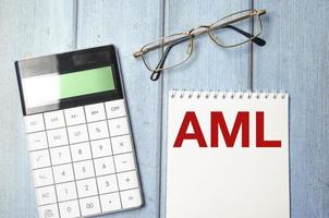 AML Anti-Money Laundering text on notepad and glasses, calculator on wooden background photo