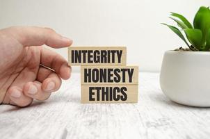 INTEGRITY, HONESTY, ETHICS words on wooden blocks and hand photo