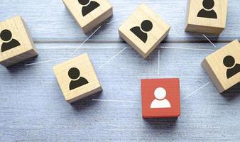 Red wooden cube with person icon stand out from the crowd on blue background. photo