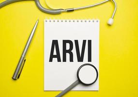 On a yellow background, a stethoscope and a white notepad with the inscription arvi. Medical concept photo