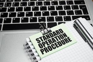 Laptop and paper and paper with the inscription - Standard Operating Procedure photo