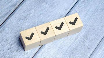 Checklist and check mark concept. Check mark on wooden blocks on light blue background photo