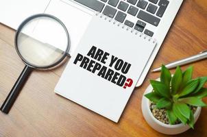 Are You Prepared text on notepad and laptop on wooden background photo