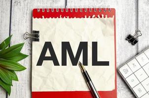 AML Anti-Money Laundering words on notepad and pen on wooden background photo