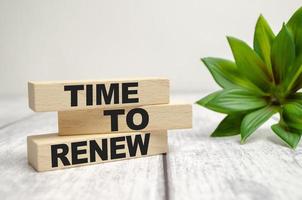 The word TIME FOR RENEW is written on a wooden blocks on white desk photo