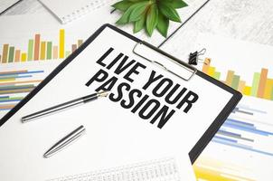 LIVE YOUR PASSION text on file folder and charts on wooden background photo