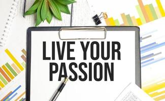 LIVE YOUR PASSION text on file folder and charts on wooden background photo